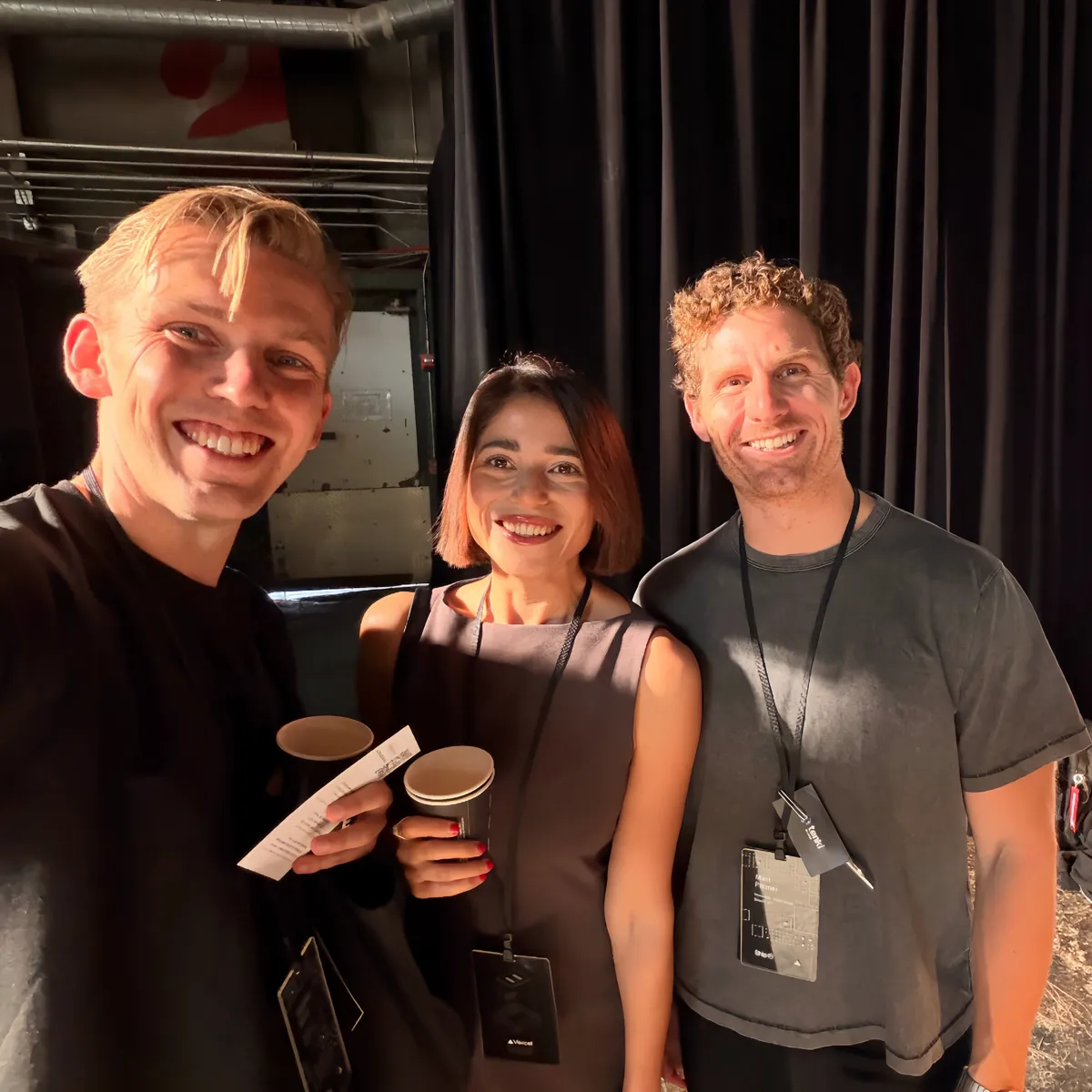 Selfie of Jono, Sne holding a coffee cup, and Matt Palmer from Cursor in front of a black stage curtain